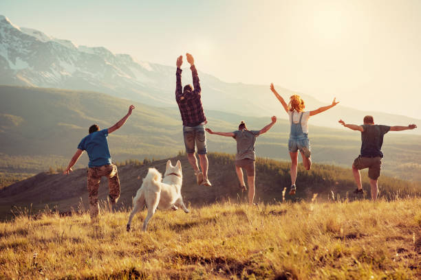 Group of happy friends are having fun, runs and jumps in mountains at sunset